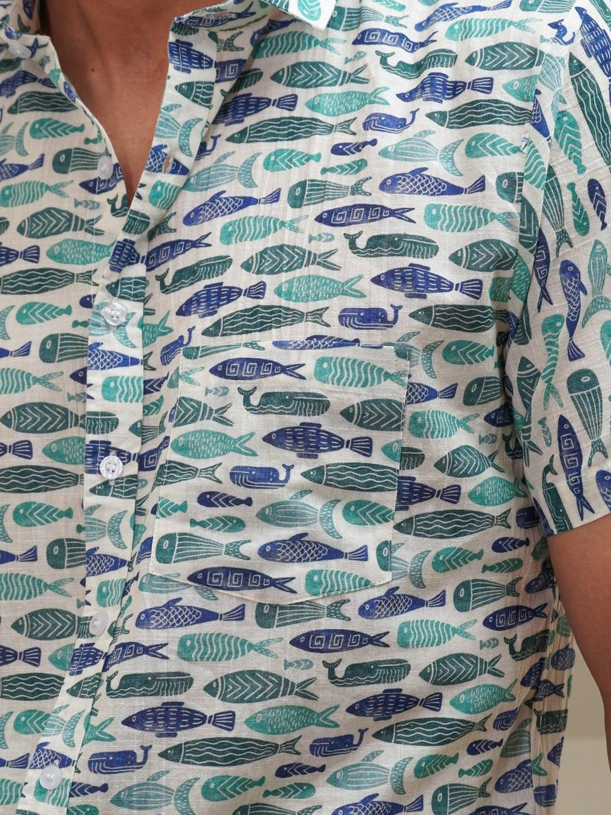 Close-up of green teal and blue fish motifs on off-white fabric