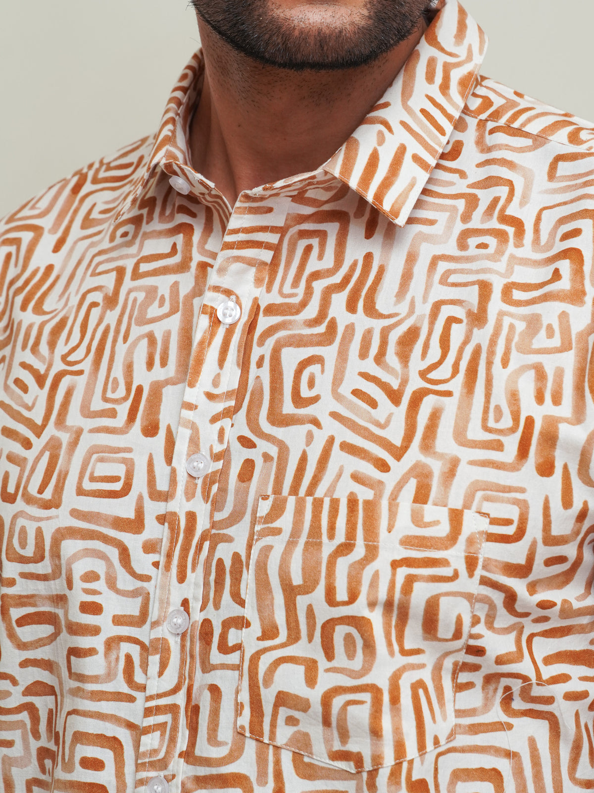 Close-up of orange brown maze-like box print on cream cotton shirt