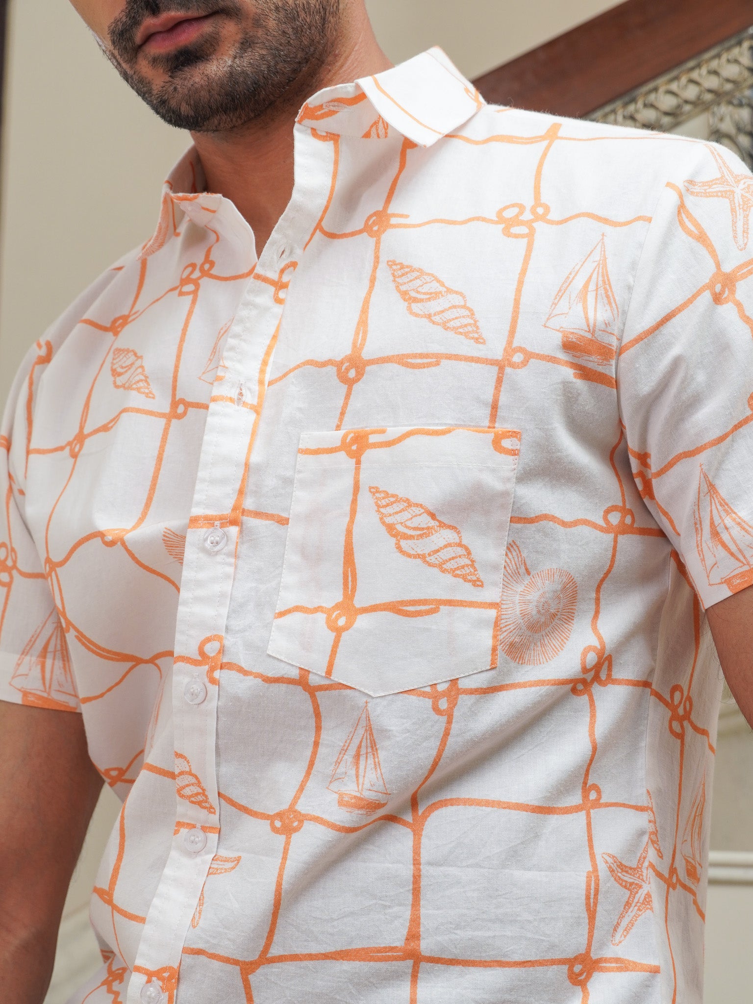 Close-up of peach orange box print and nautical motifs on white cotton shirt