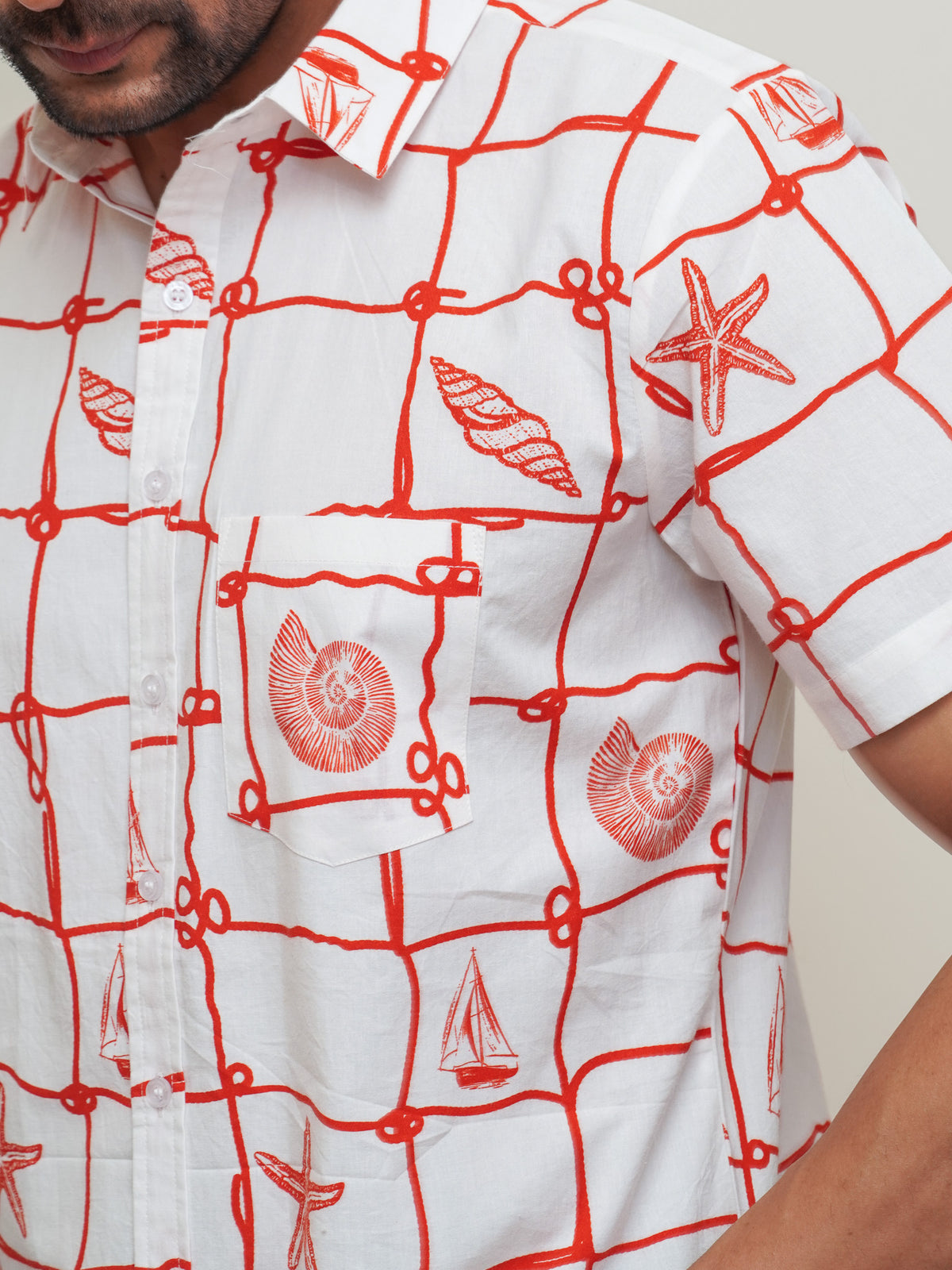 Close-up of red sailboat rope shell and starfish print on white cotton shirt