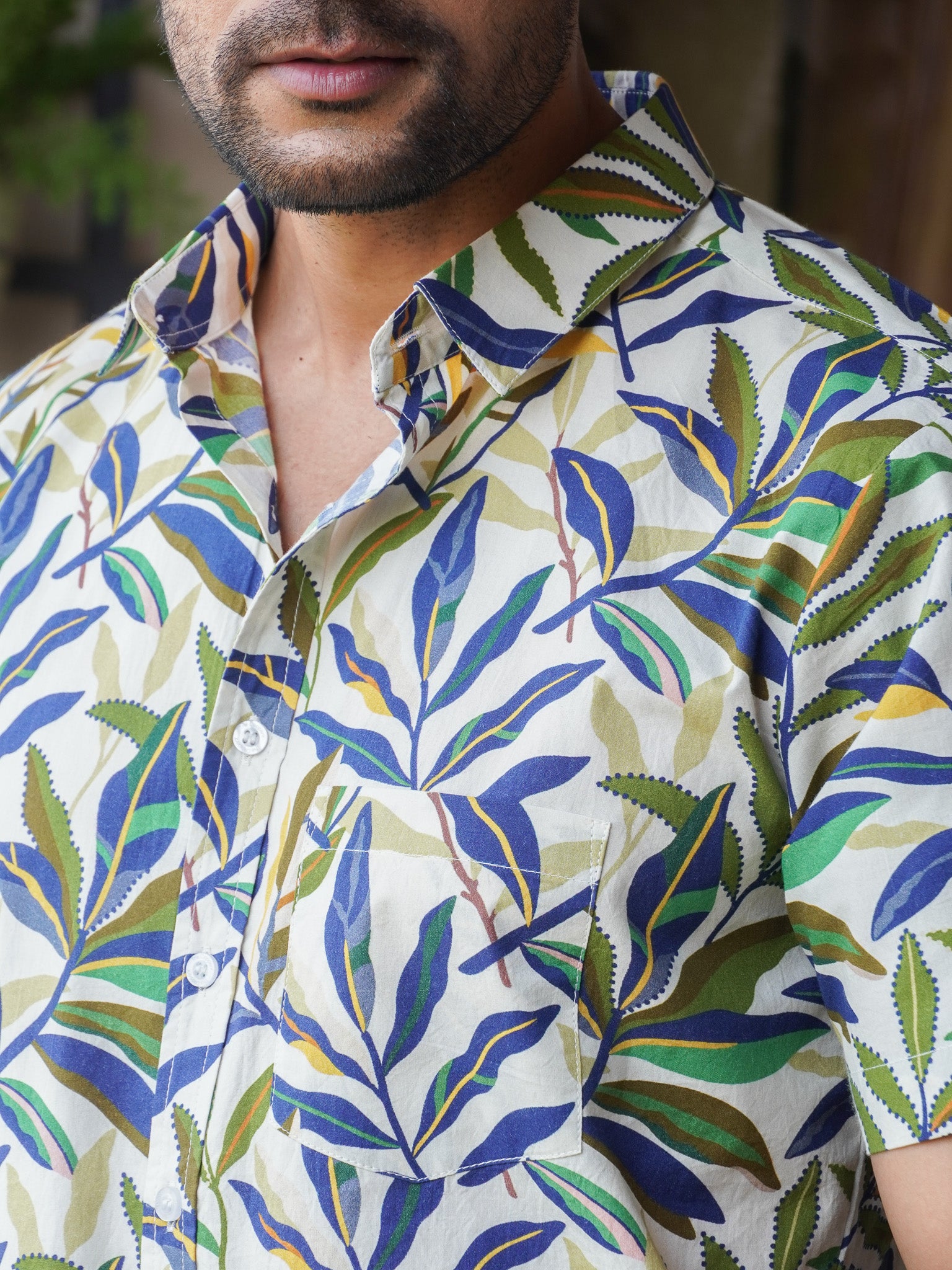 Close-up of green blue and yellow tropical leaf print on white cotton shirt